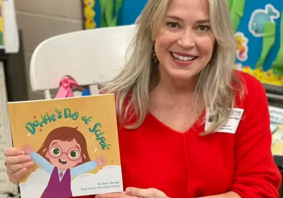 A woman holding up a book with a picture of a girl.