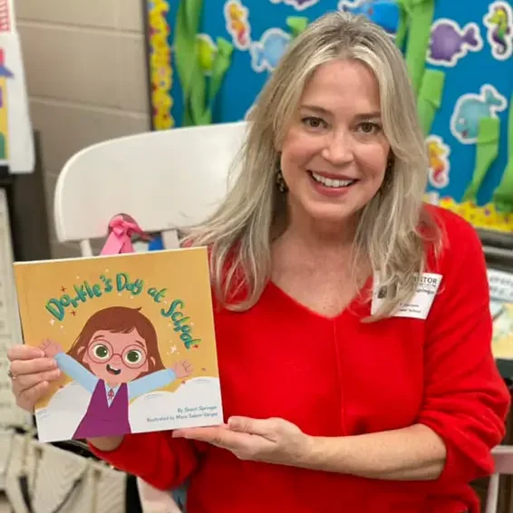 A woman holding up a book with a picture of a girl.